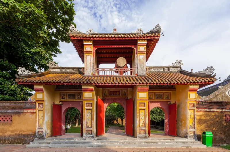 Cổng vàng đỏ với tháp trống nổi bật trong Hoàng thành Huế, Việt Nam.