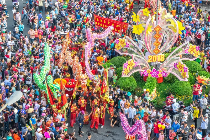Cảnh trên cao đoàn múa lân sư rồng sặc sỡ diễu hành giữa dòng người đông đúc trong lễ hội Việt Nam.