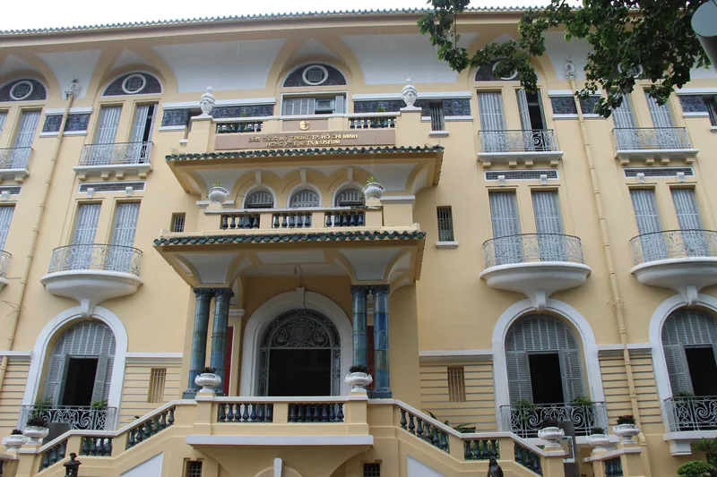 Mặt tiền vàng kiểu thuộc địa của Bảo tàng Mỹ thuật Thành phố Hồ Chí Minh với cửa sổ vòm và ban công.